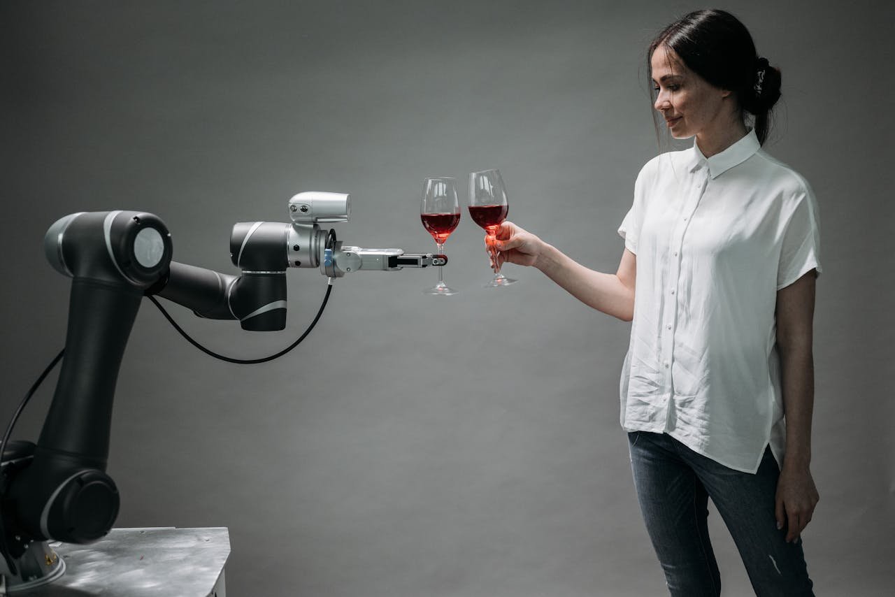 A woman in casual attire shares a toast with an advanced robotic arm, reflecting modern technology and innovation in robotics.